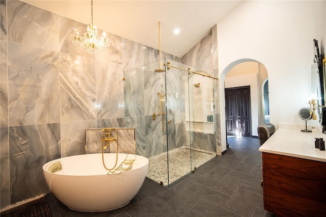 full bath with vanity, a shower with door, tile walls, a towering ceiling, and a freestanding bath