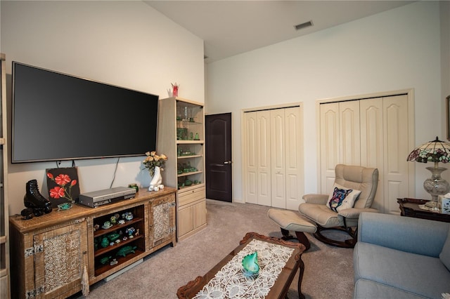 carpeted living room with high vaulted ceiling and visible vents