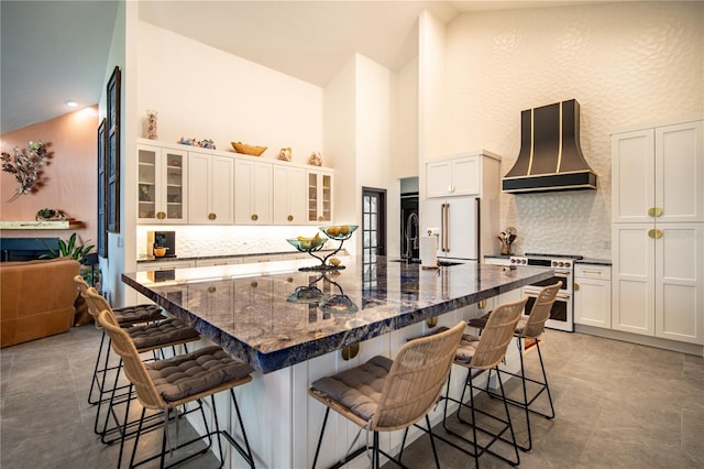 kitchen with a kitchen bar, backsplash, high end appliances, high vaulted ceiling, and premium range hood