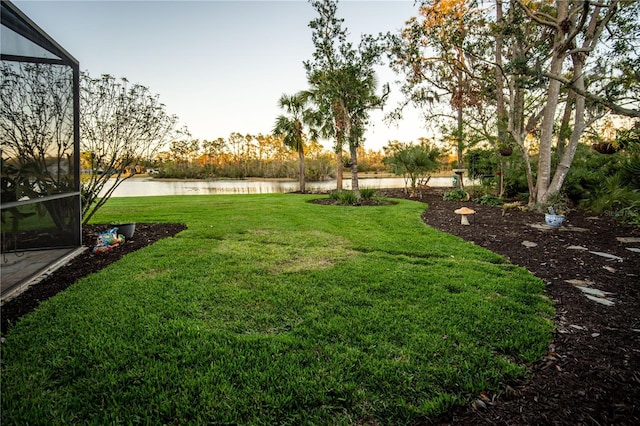 view of yard with glass enclosure and a water view
