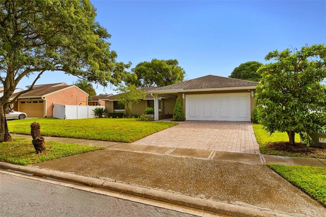 ranch-style home with a garage, fence, decorative driveway, a front lawn, and stucco siding