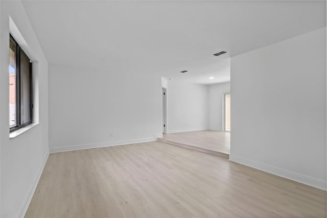 unfurnished room featuring light wood-type flooring, visible vents, and baseboards