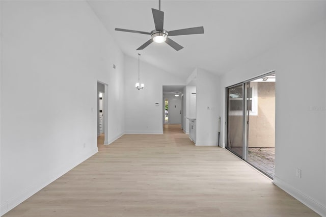 empty room with high vaulted ceiling, light wood-type flooring, baseboards, and ceiling fan with notable chandelier