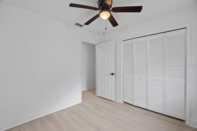 unfurnished bedroom featuring a closet, visible vents, light wood-style floors, a ceiling fan, and baseboards