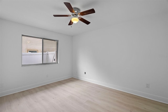 empty room with light wood finished floors, a ceiling fan, and baseboards