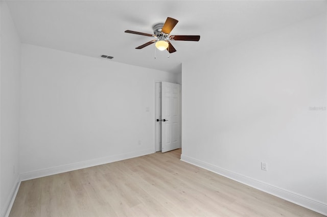 spare room with ceiling fan, light wood finished floors, visible vents, and baseboards