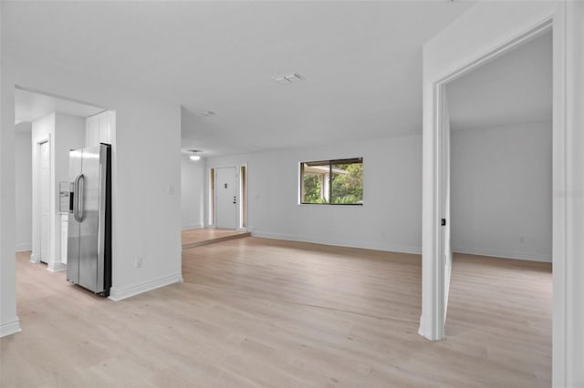 interior space with light wood-type flooring, visible vents, and baseboards