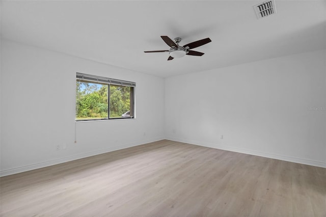 spare room featuring baseboards, a ceiling fan, visible vents, and light wood-style floors