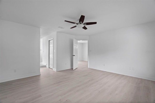 unfurnished room with a ceiling fan, visible vents, light wood-style flooring, and baseboards