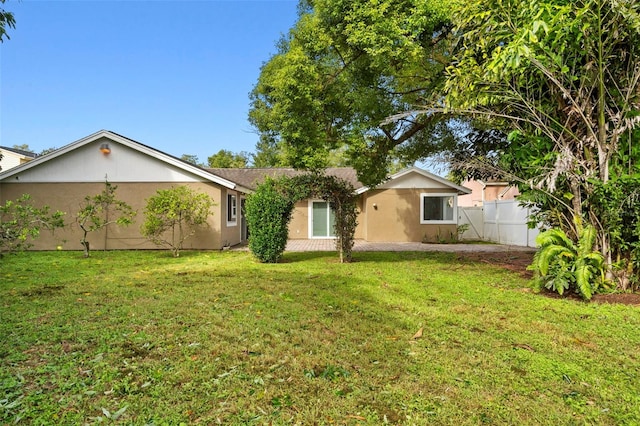 view of front facade with a front yard, fence, and stucco siding