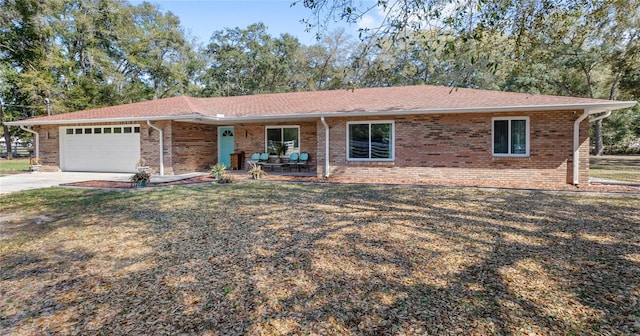 ranch-style home with a garage, a front yard, concrete driveway, and brick siding