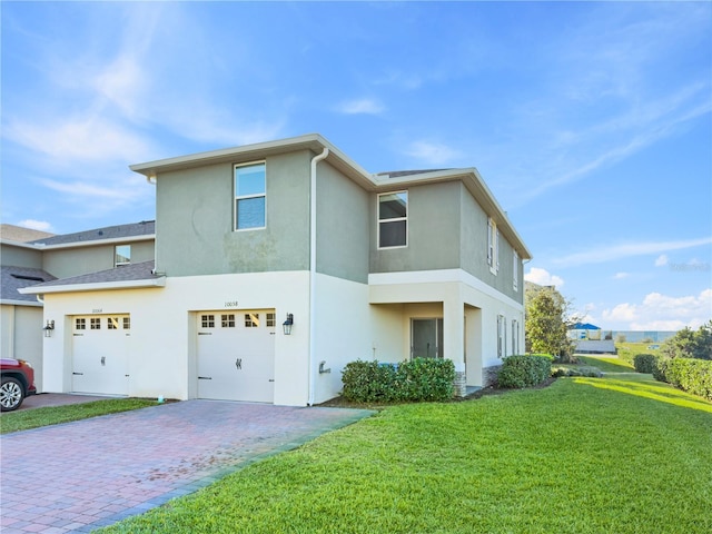 view of front of property with a front lawn, decorative driveway, an attached garage, and stucco siding