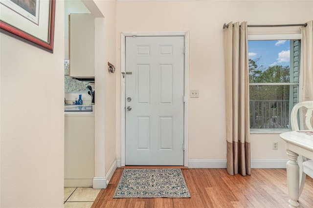 entrance foyer featuring washer / clothes dryer, light wood-style flooring, and baseboards