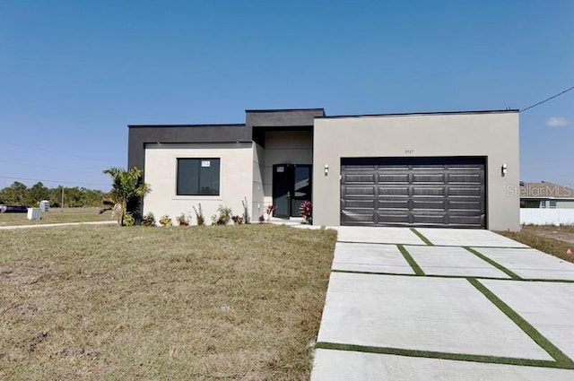 contemporary house featuring a garage, a front yard, concrete driveway, and stucco siding