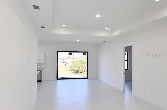 unfurnished room with recessed lighting, a raised ceiling, visible vents, and baseboards