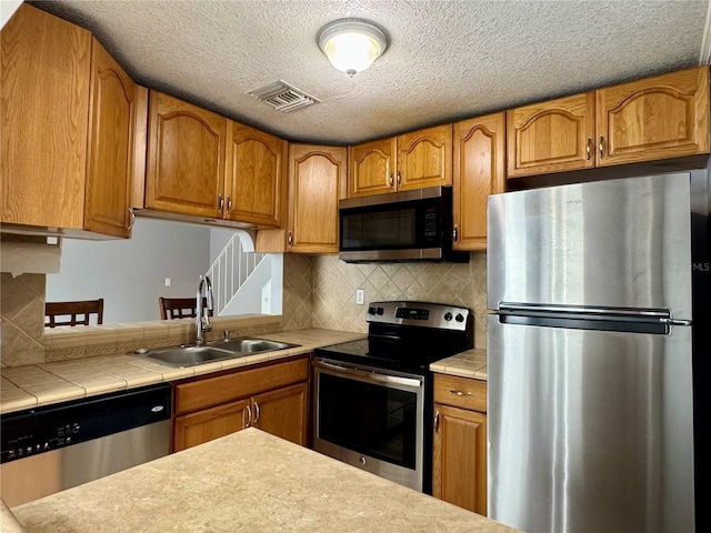 kitchen with visible vents, appliances with stainless steel finishes, brown cabinets, and a sink