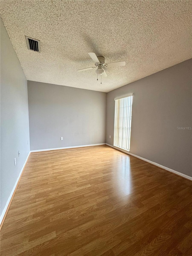 spare room with visible vents, ceiling fan, baseboards, and wood finished floors