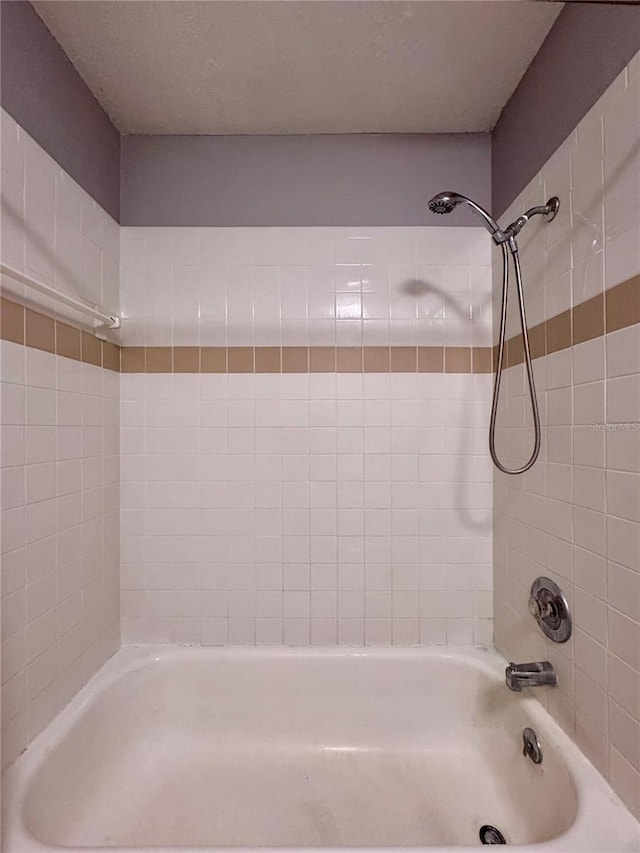 bathroom with a textured ceiling and bathing tub / shower combination