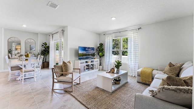 living area with visible vents, a textured ceiling, and light tile patterned flooring