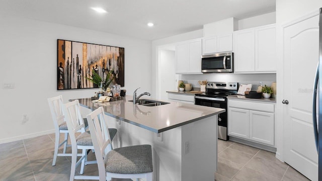 kitchen featuring appliances with stainless steel finishes, white cabinets, a kitchen island with sink, and a sink