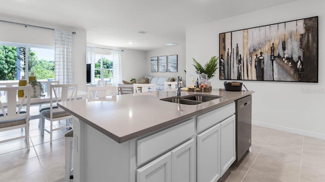 kitchen with light tile patterned floors, a center island with sink, dishwasher, white cabinetry, and a sink