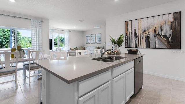 kitchen featuring light tile patterned floors, light countertops, a kitchen island with sink, a sink, and dishwasher