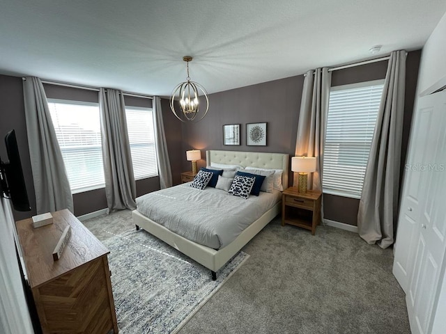 carpeted bedroom with an inviting chandelier and baseboards