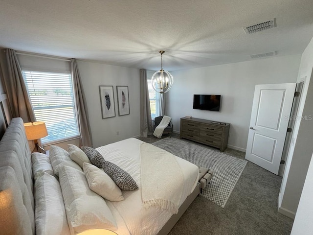 carpeted bedroom with a chandelier, a textured ceiling, visible vents, and baseboards