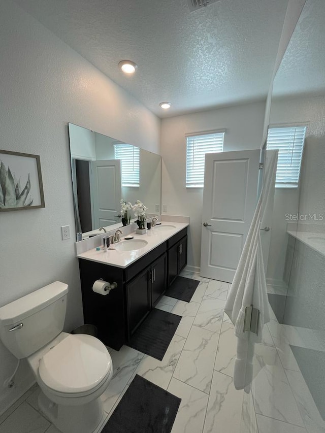 bathroom with toilet, marble finish floor, a textured ceiling, and a sink