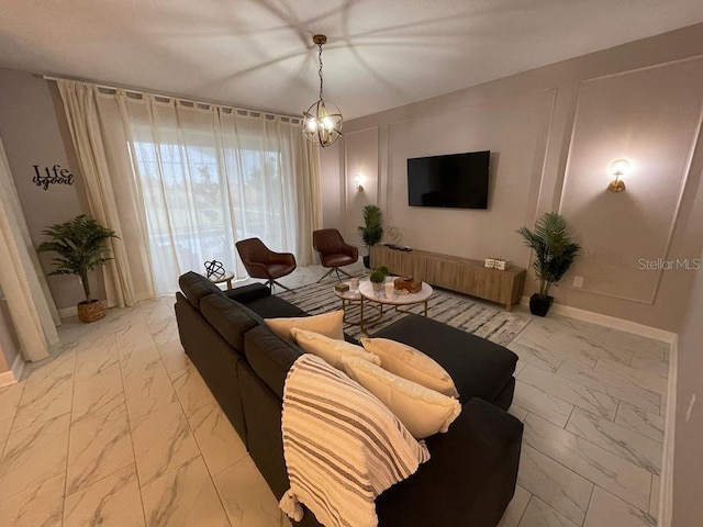 living area with marble finish floor, baseboards, a decorative wall, and a notable chandelier