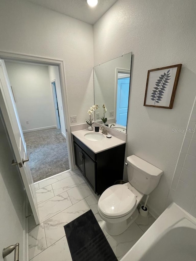 bathroom featuring toilet, vanity, baseboards, marble finish floor, and a bath