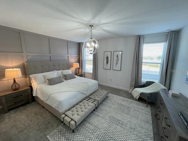 carpeted bedroom featuring a textured ceiling, multiple windows, an inviting chandelier, and a decorative wall