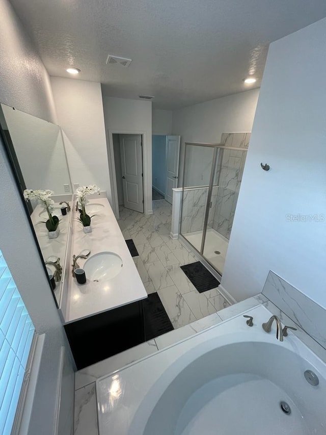 bathroom featuring marble finish floor, visible vents, a sink, a shower stall, and a textured ceiling