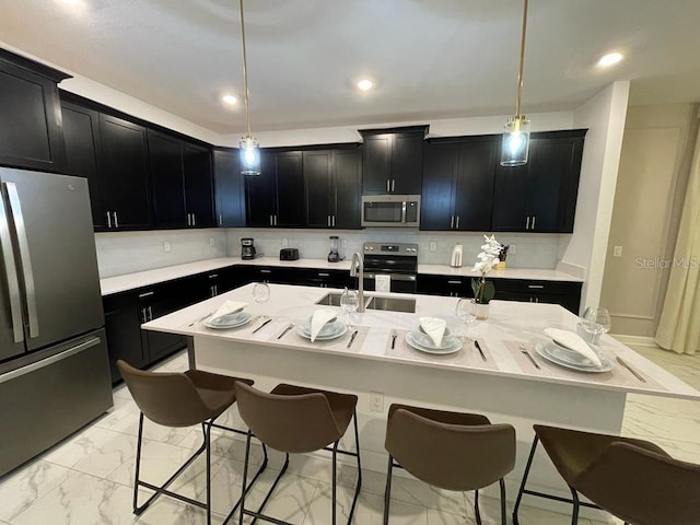 kitchen featuring marble finish floor, a breakfast bar area, appliances with stainless steel finishes, and dark cabinetry