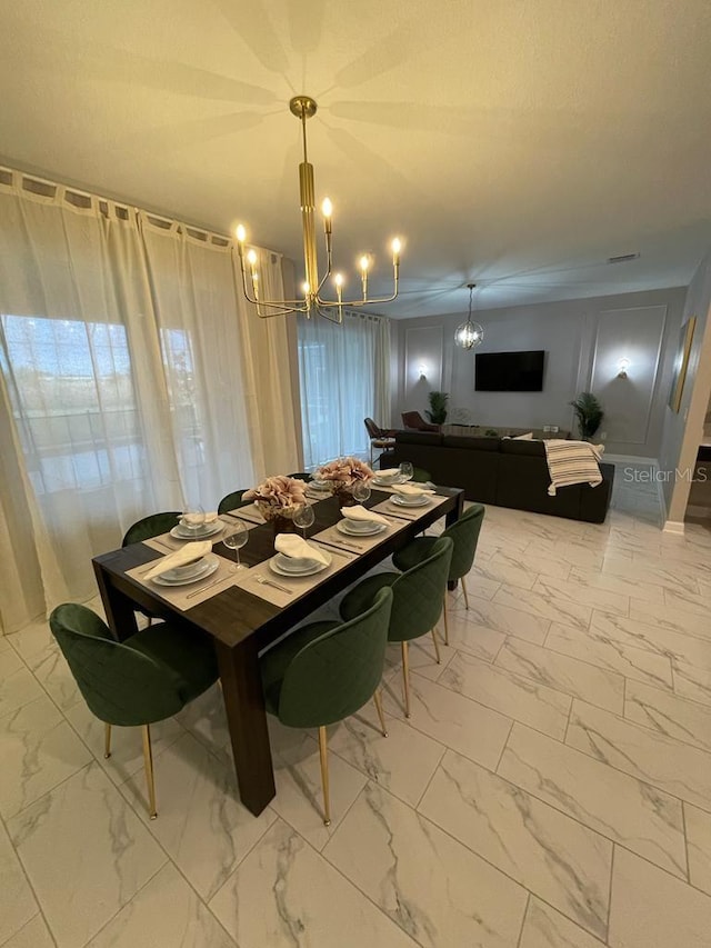 dining area featuring marble finish floor, visible vents, and a notable chandelier