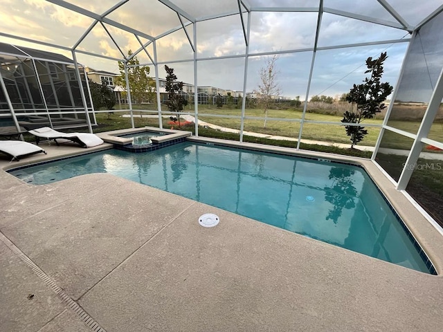 view of pool featuring a patio area, glass enclosure, and a pool with connected hot tub