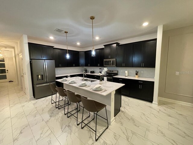 kitchen with marble finish floor, light countertops, appliances with stainless steel finishes, dark cabinetry, and a kitchen breakfast bar