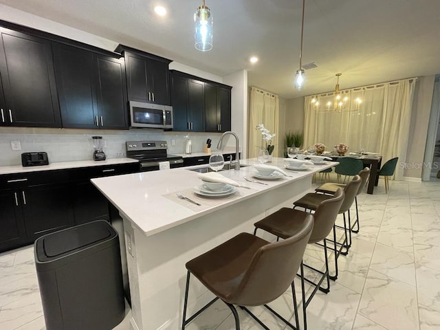 kitchen with marble finish floor, appliances with stainless steel finishes, a sink, and dark cabinetry