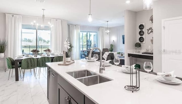 kitchen with decorative light fixtures, a sink, marble finish floor, light countertops, and a notable chandelier