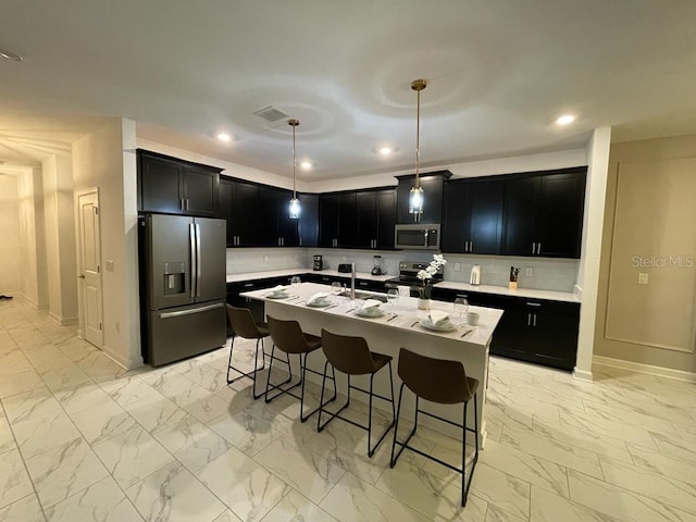 kitchen with marble finish floor, appliances with stainless steel finishes, a kitchen bar, and dark cabinetry