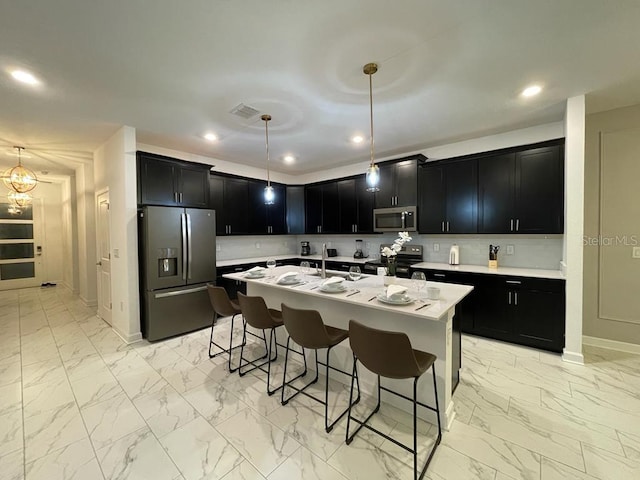 kitchen featuring marble finish floor, stainless steel appliances, and dark cabinetry