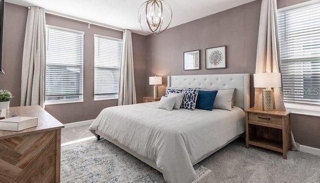 carpeted bedroom featuring a notable chandelier and baseboards