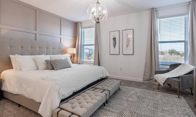 carpeted bedroom with a notable chandelier, baseboards, and a decorative wall