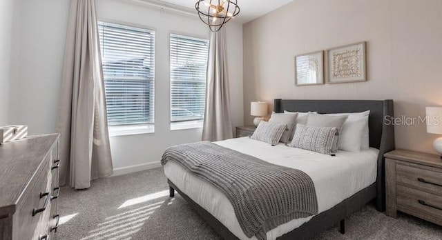 carpeted bedroom featuring baseboards and an inviting chandelier