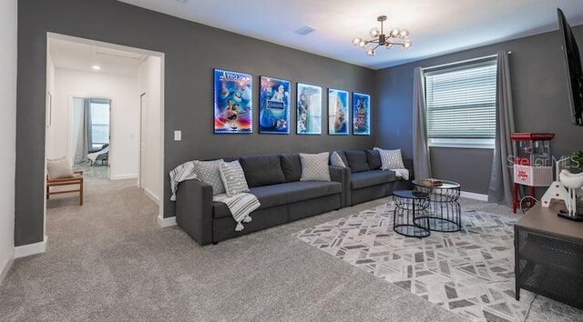 carpeted living area featuring baseboards, attic access, and a notable chandelier