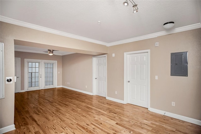 spare room with ornamental molding, light wood-type flooring, electric panel, and baseboards