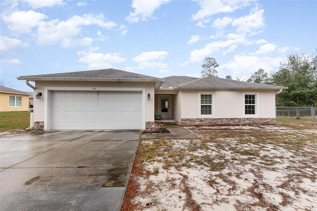 view of front facade featuring a garage, fence, concrete driveway, and stucco siding