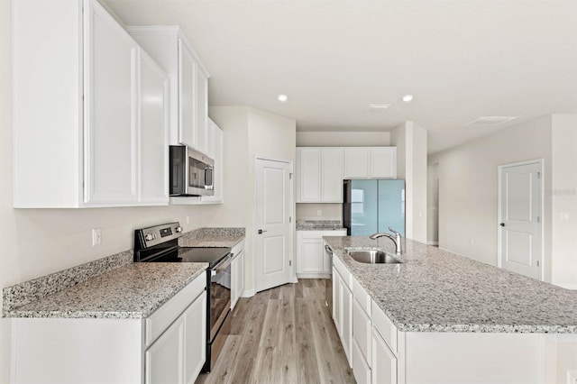 kitchen with appliances with stainless steel finishes, a sink, a center island with sink, and white cabinetry