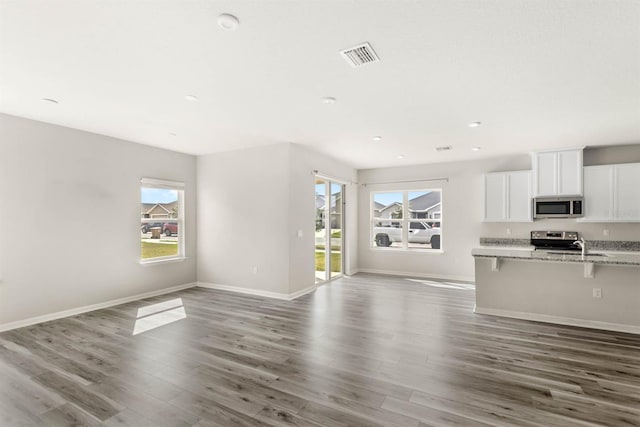 unfurnished living room with dark wood-style floors, visible vents, and baseboards