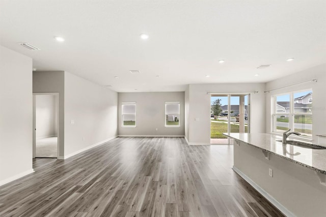 unfurnished living room featuring dark wood finished floors, a sink, visible vents, and baseboards